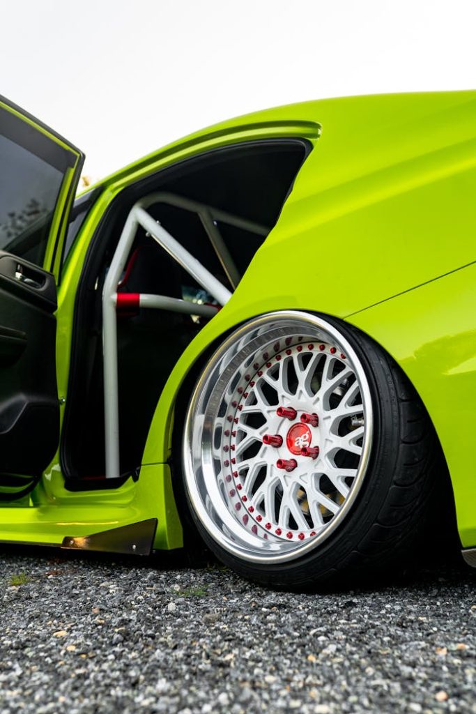Close-up of a vibrant green modified car with custom wheels and visible roll cage, showcasing automotive design.
